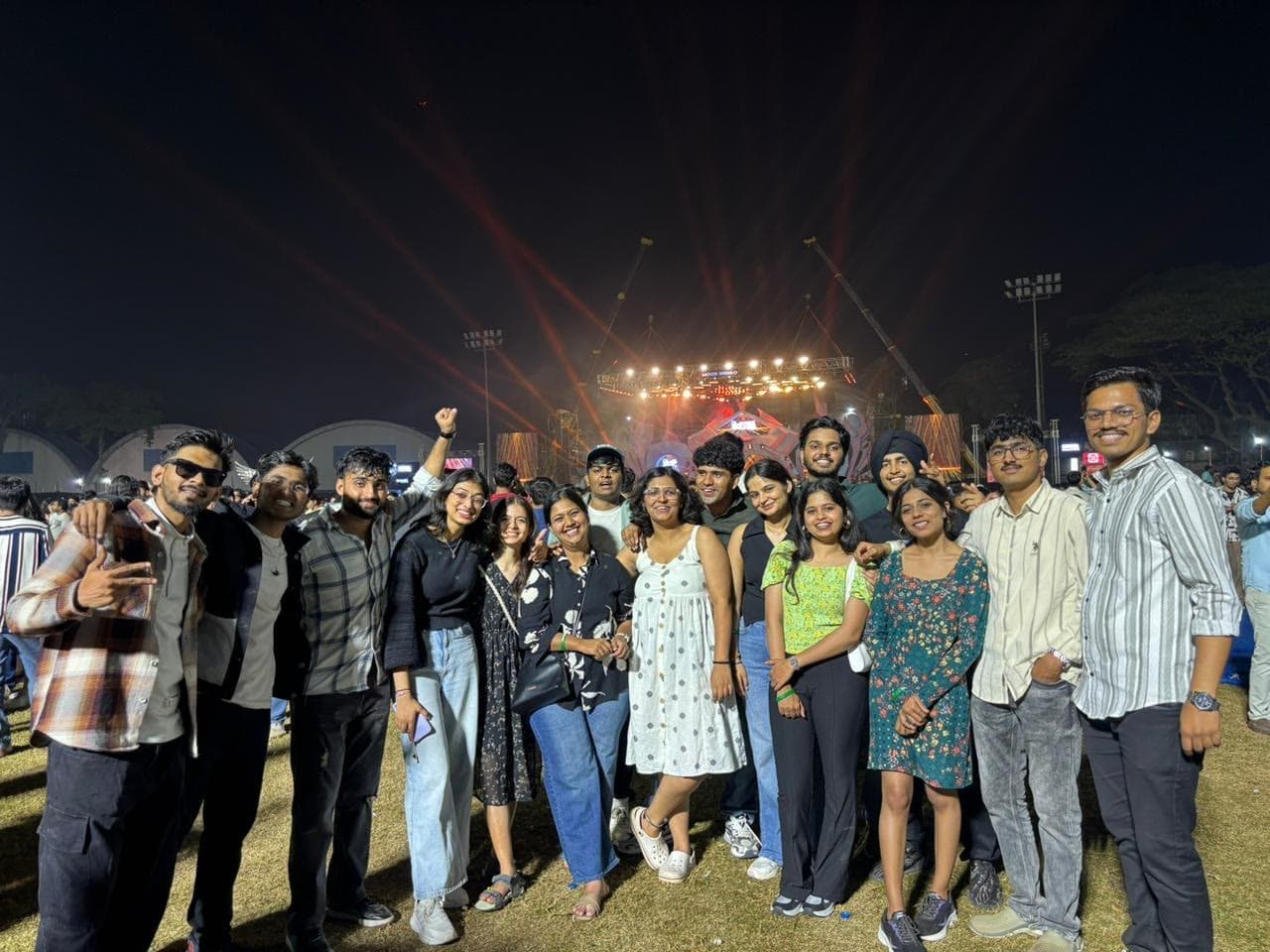 The group in front of the main stage at night, lights fanning out behind them