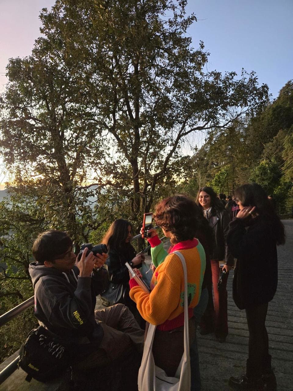 The group at a hill viewpoint at golden hour, cameras out