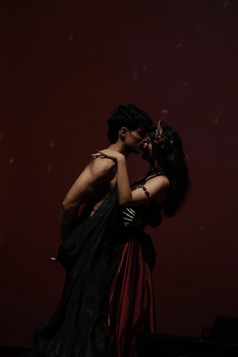 A pair mid-performance in red and black against a deep red wash
